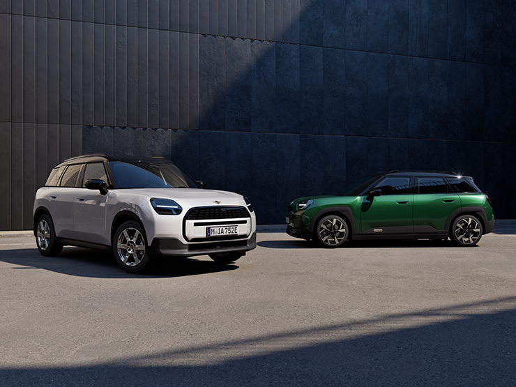 Two MINI Countryman models parked side by side, one in Nanuq White Metallic and one in British Racing Green IV Metallic.