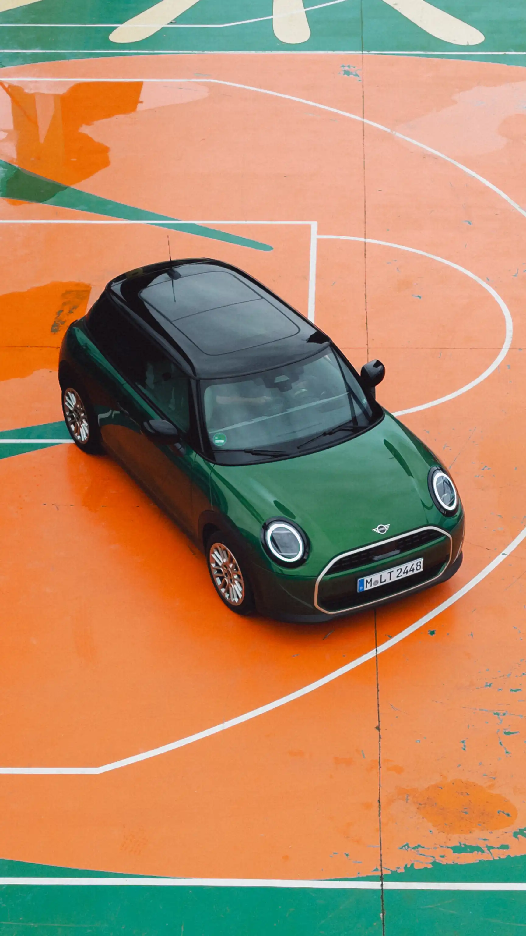 MINI Cooper in Racing Green IV with a black roof parked on an orange basketball court.