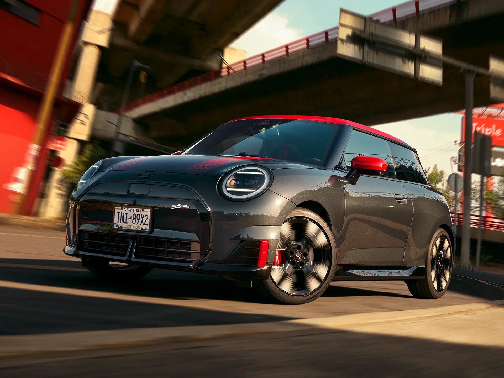 MINI John Cooper Works in Midnight Black II with Chili Red roof driving on an urban road.