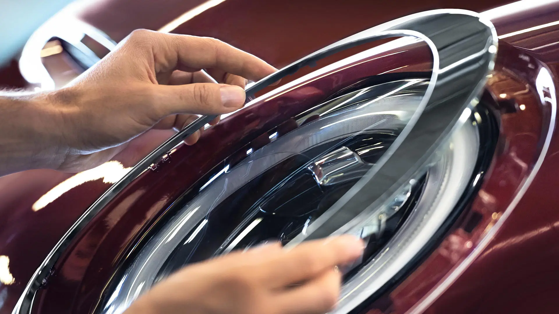 Hands fitting a trim ring around a MINI headlight.