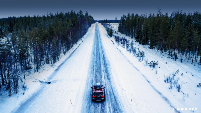 MINI Cooper with a top roof rack on a road in the snow rear view.