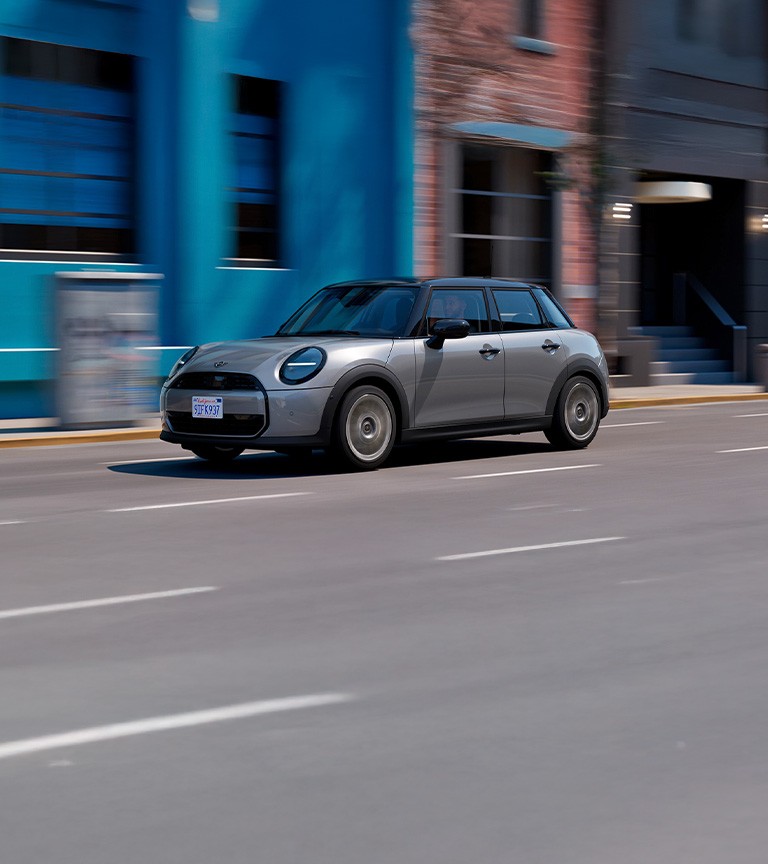 MINI Cooper 5‑Door in Nanuq White Metallic driving on an urban street.