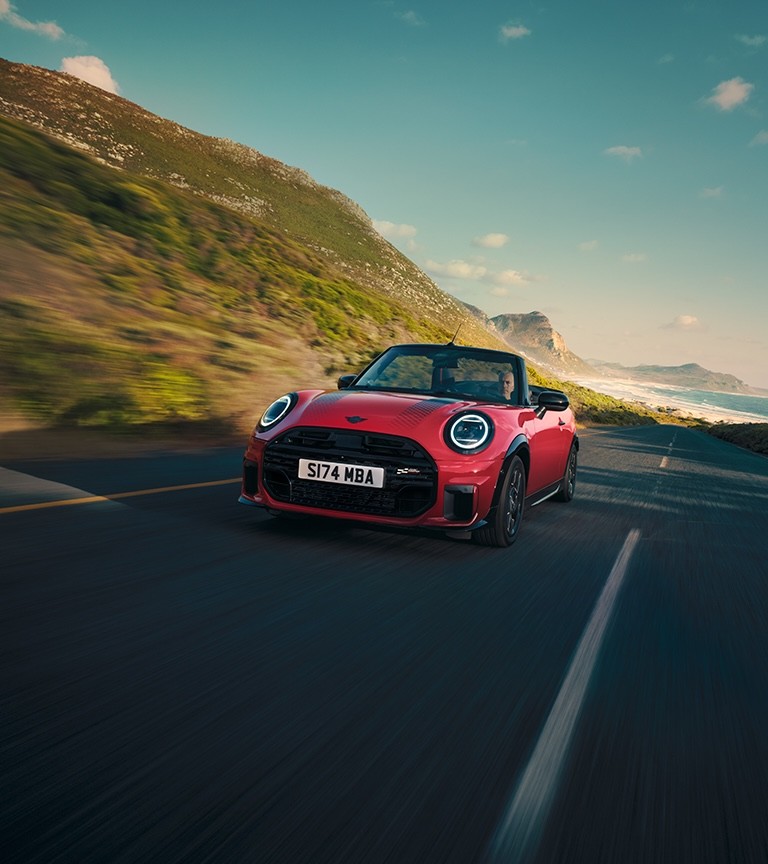 MINI Convertible John Cooper Works in Chili Red driving along a coastal road.